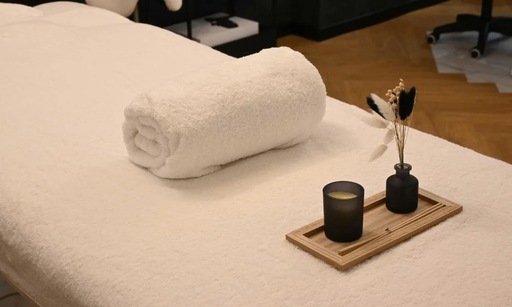 Coimbatore spa hotel with a clean massage table, rolled towel, candle, and spa decor.